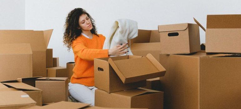 A woman with curly hair unpacks boxes in her new apartment.