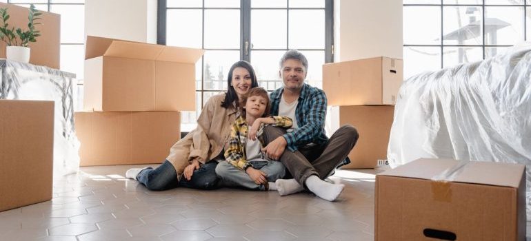 A joyful family sitting together amidst moving boxes, marking a new beginning in their home.